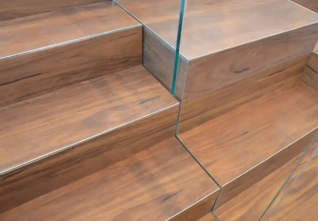 Close-up of modern wooden stairs with clean lines and a glass railing, featuring natural wood grain patterns and smooth surfaces.
