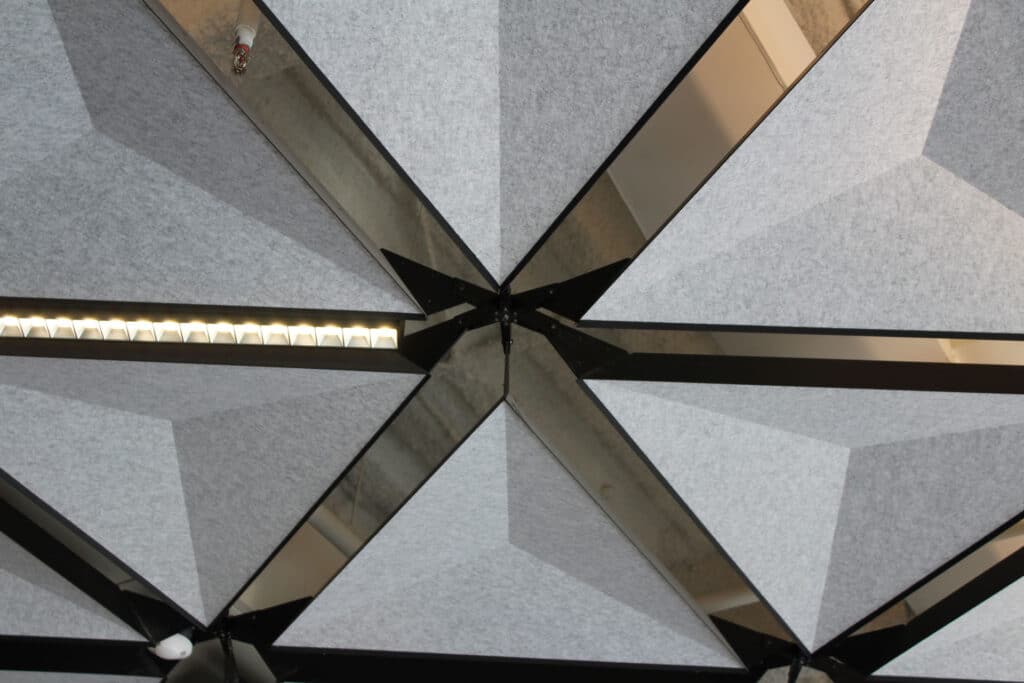Geometric ceiling design with gray panels and black borders forming a star-like pattern, featuring LED light strips and a small sprinkler head.